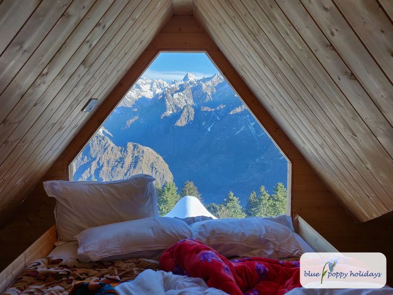 Bed under a triangular window looking out over the mountains